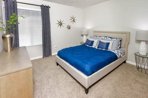 Apartments for Rent in Downey CA - Park Regency Club - Bedroom with Dresser, Nightstands, Lamps, Bed, Carpet Flooring, and Window.