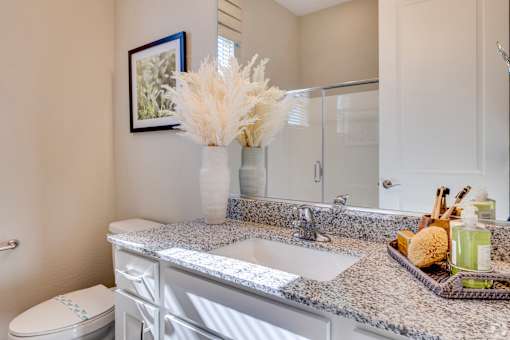 A bathroom with a toilet, sink, and a vase with white flowers.