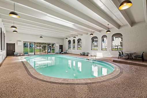 A large indoor swimming pool with a brown floor and white walls.