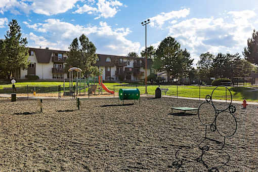 A playground with a sandy area and a swing set.