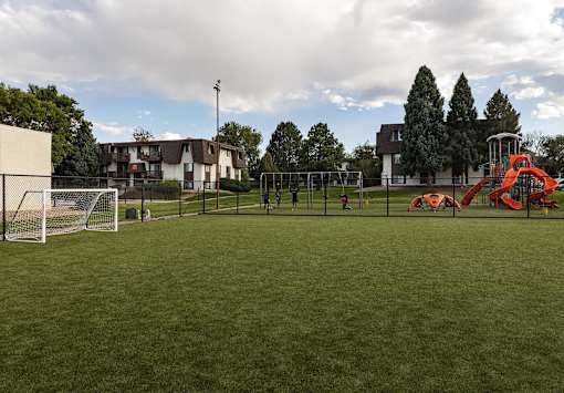 A playground with a red slide and a soccer goal.