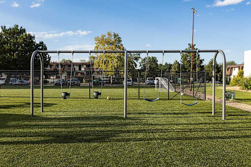 A playground with swings and a seesaw in the foreground.