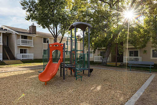 A playground with a red slide and a green swing set.