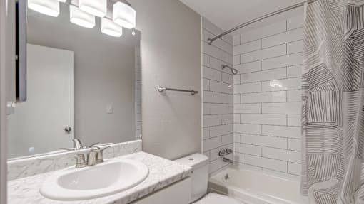 A white bathroom with a sink, toilet, and shower.