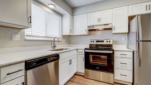Aurora, CO Apartments – Ivy Crossing – A modern kitchen with white cabinets and stainless steel appliances.