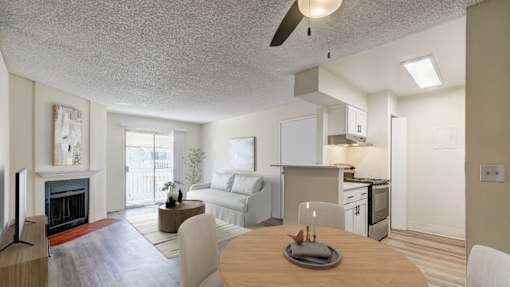 Aurora, CO Apartments – Ivy Crossing – A modern living room with a fireplace and a dining table set for two.