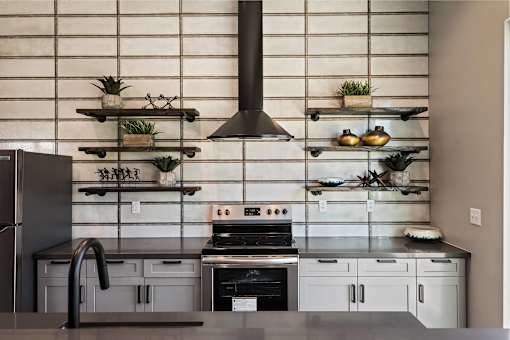 A modern kitchen with a black range hood and a black faucet.