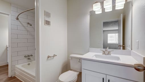 Aurora, CO Apartments – Ivy Crossing – A white bathroom with a toilet, sink, and shower.