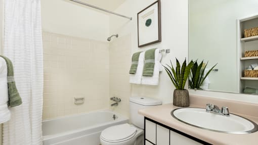A bathroom with a white toilet, a white bathtub, a white sink, and a white shower curtain.