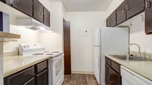 A kitchen with white appliances and brown cabinets.