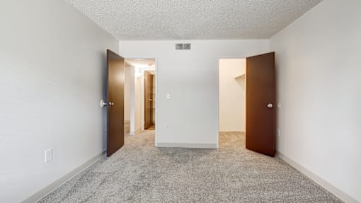 A room with a carpeted floor and two doors.