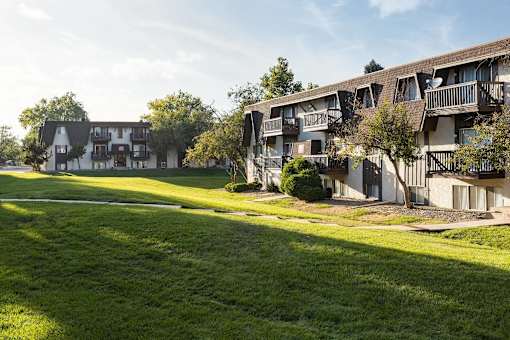 A row of apartment buildings with green lawns in front.