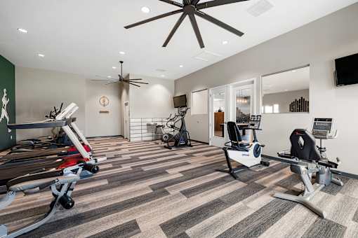 Aurora, CO Apartments – Ivy Crossing – A gym with treadmills, exercise bikes, and a ceiling fan.