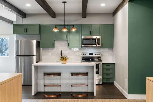 A kitchen with green cabinets and a white island.