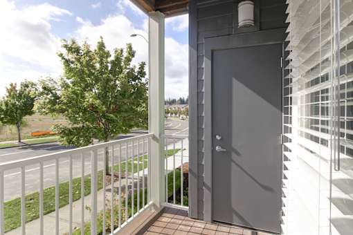 A balcony with a white railing and a grey door.