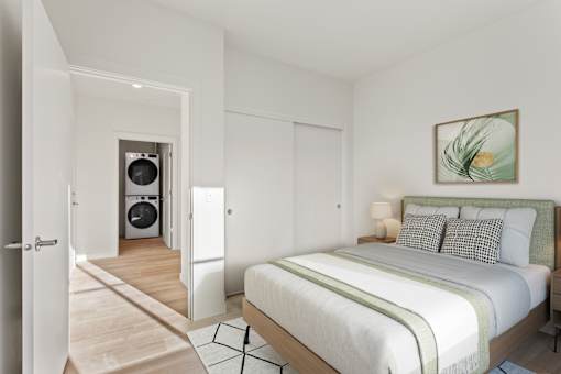 A bedroom with a large bed and a washing machine in the laundry area.