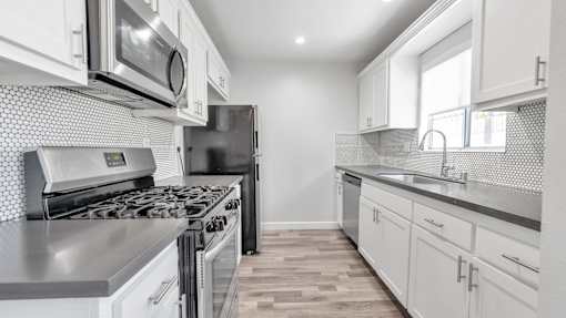 A modern kitchen with white cabinets and stainless steel appliances.