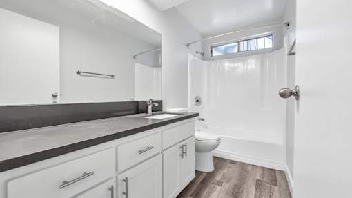 A white bathroom with a toilet, sink, and a shower.