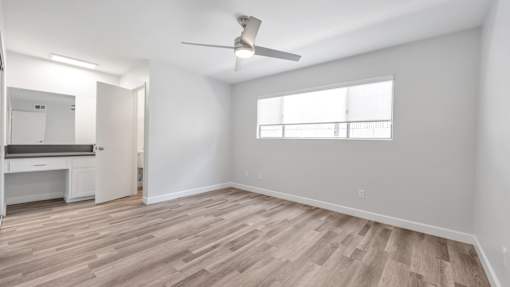 A room with a ceiling fan and a window with blinds.