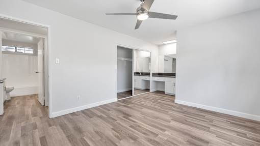 A room with a ceiling fan and wooden flooring.