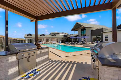 A pool area with a grill and a building in the background.