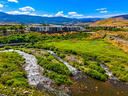 A river flows through a green valley with mountains in the background.