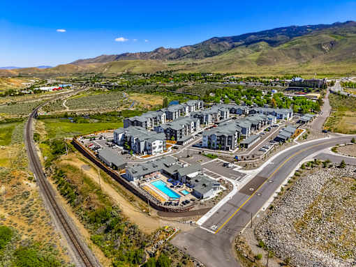 A large building complex with a swimming pool in the foreground and a winding road in the background.