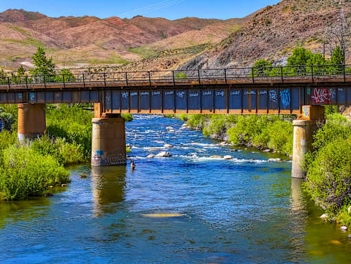 A bridge over a river with a mountain in the background.