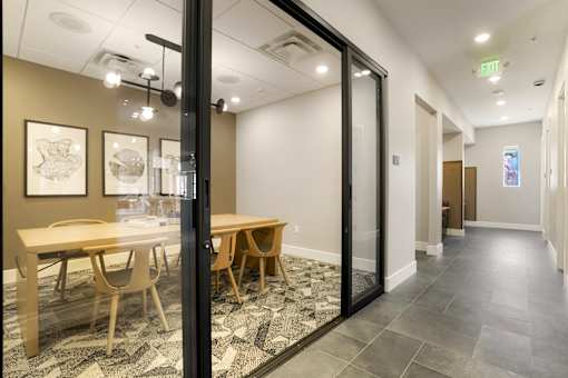 A conference room with a glass door and a table with chairs.
