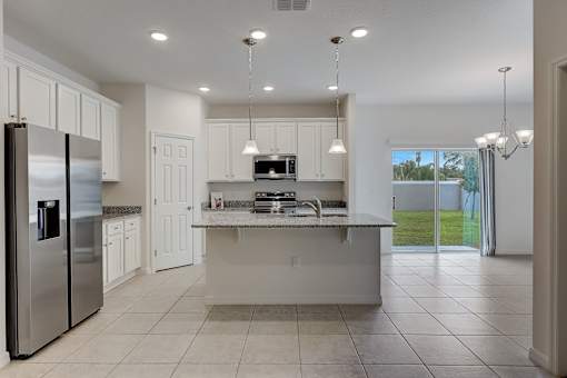 A modern kitchen with a refrigerator, sink, and cabinets.