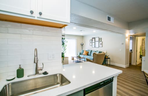the view of the kitchen and living room from the kitchen counter top with a sink