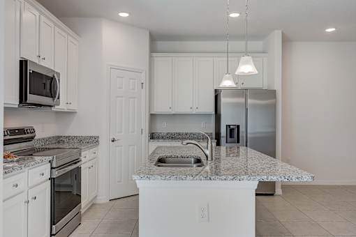 A kitchen with white cabinets and a marble countertop.
