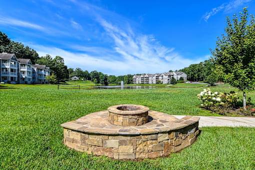 A stone fire pit sits in the middle of a grassy area.