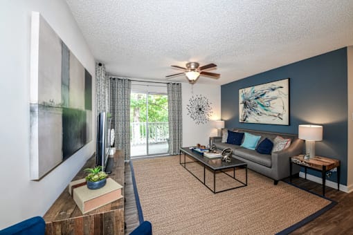 A living room with a grey couch, a coffee table, and a ceiling fan.