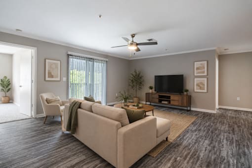 Bright open-concept living room at Lancaster Place Apartments in Calera, Alabama featuring wood-style flooring, abundant natural light, and a spacious layout.