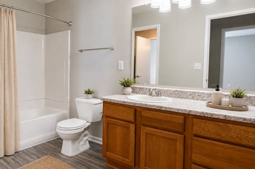 Modern apartment bathroom at Lancaster Place Apartments in Calera, Alabama with an oversized vanity, full bathtub, and updated fixtures.
