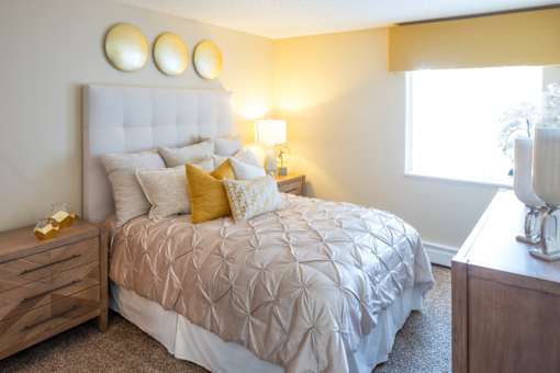 A bedroom with a large bed, a nightstand, and a window.