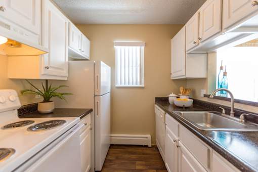 A kitchen with white cabinets and a black countertop.