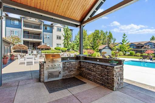 A patio with a stone wall and a grill is shown.