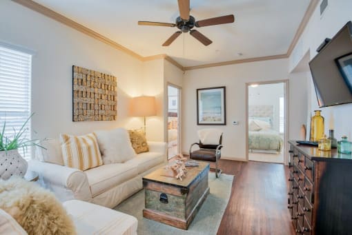 Living room with wood floors and couches and chairs and windows with blinds and ceiling light/fan