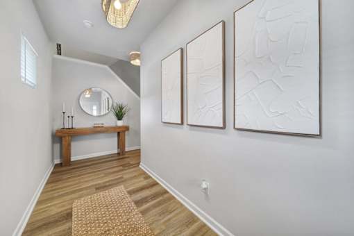 Hallway in Indian Trail, NC townhome with vinyl plank wood flooring, bench, mirror, and framed wall art