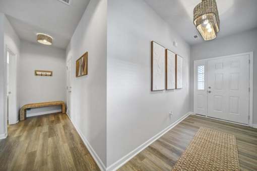 Hallway in Indian Trail, NC townhome with vinyl plank wood flooring, bench, and framed pictures