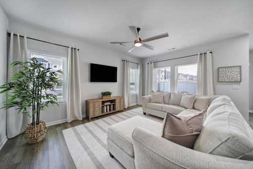 Living room in Indian Trail, NC townhome with beige couch, television, ceiling fan, and vinyl plank wood flooring