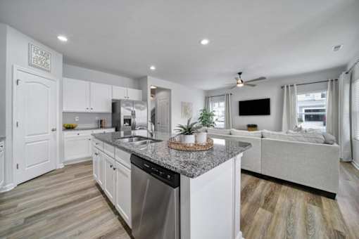 Modern kitchen in Indian Trail, NC townhome with granite countertops, stainless steel appliances, island, and open view to living room