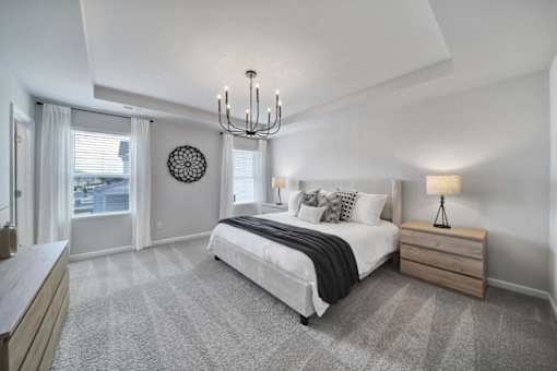 Spacious bedroom with large bed, chandelier, and windows in pet-friendly townhome in Indian Trail, NC