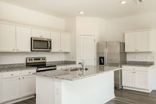 A kitchen with white cabinets and a granite countertop.