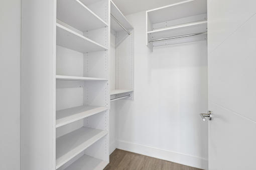 Large walk-in closet with built-in shelving at MB Station apartments in Miami, offering generous storage and organized living space.