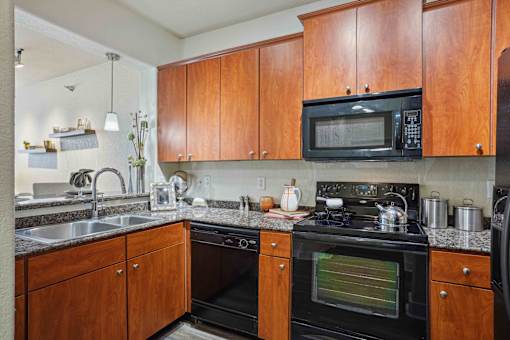 1, 2 -Bedroom Apartments for Rent in North Little Rock, AR – Metropolitan– A kitchen with wooden cabinets and a black microwave.