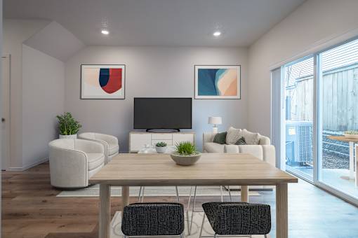 Apartments Near Vancouver Mall, WA - Minnehaha Meadows - Living Room with Vinyl Plank Flooring, Couch, Armchairs, Media Cabinet, TV, Side Table, Lamp, Framed Artworks, and a Sliding Door to the Patio.