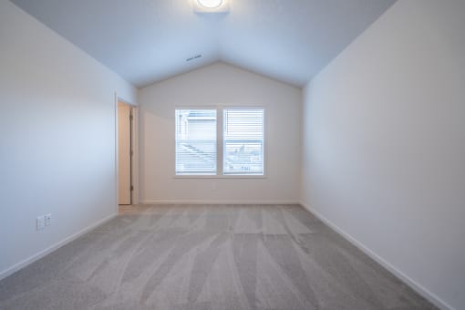 an empty bedroom with a window and a door